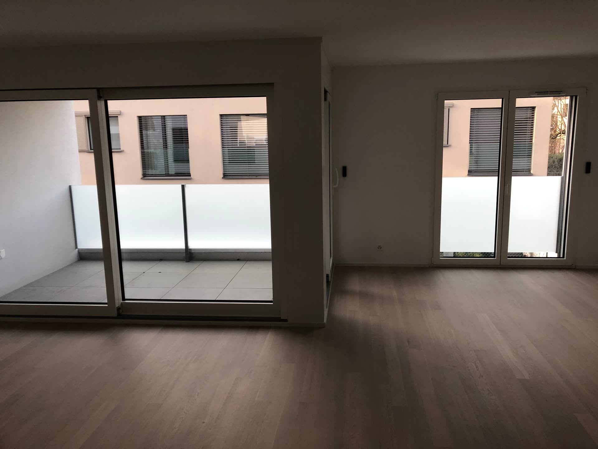 Appartement vide, garde-corps en verre dépoli visibles derrière les baies — Sous-Balme, Veyrier (GE)