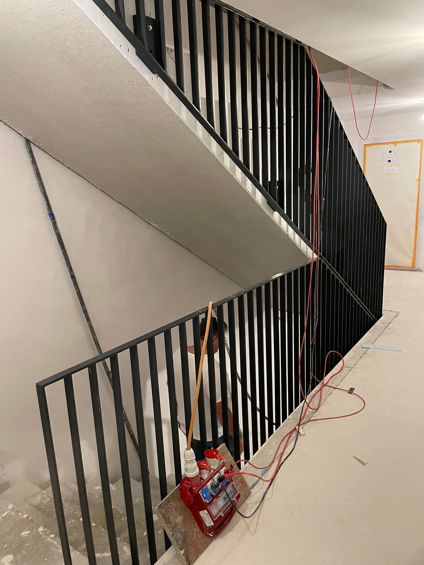Cage d’escalier en chantier : garde-corps noir à barreaux verticaux suivant la volée — Crochetan, Monthey (VS)