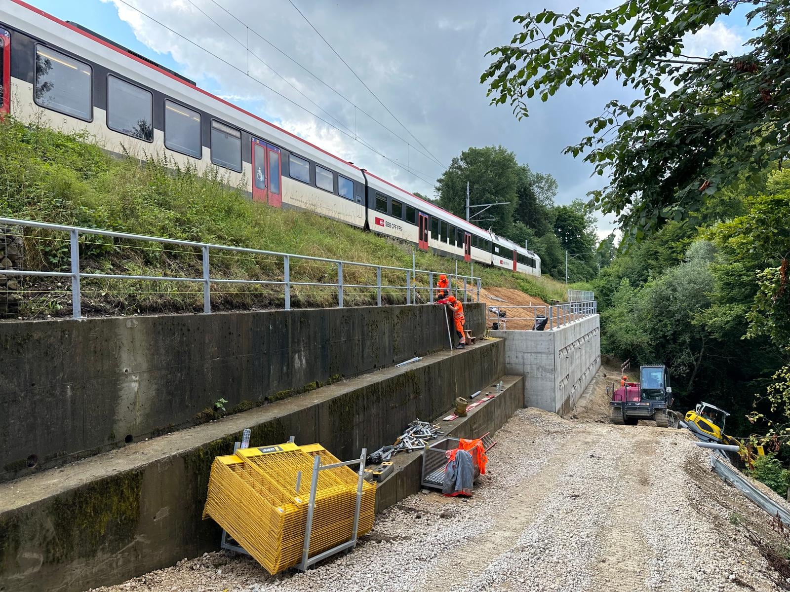 Train CFF au-dessus d’un mur de soutènement coiffé d’un garde-corps en tube galvanisé — CFF, Montagny (FR)
