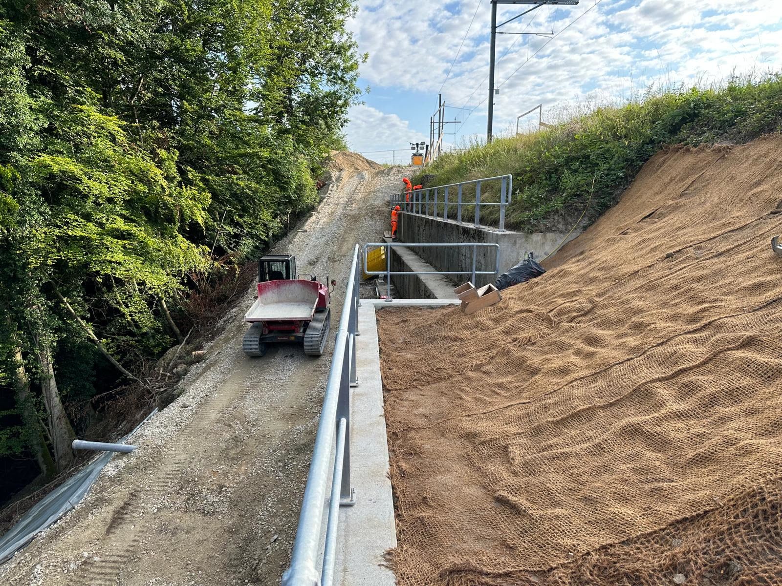 Garde-corps en tube galvanisé le long d’un mur de soutènement, talus en cours d’aménagement — CFF, Montagny (FR)