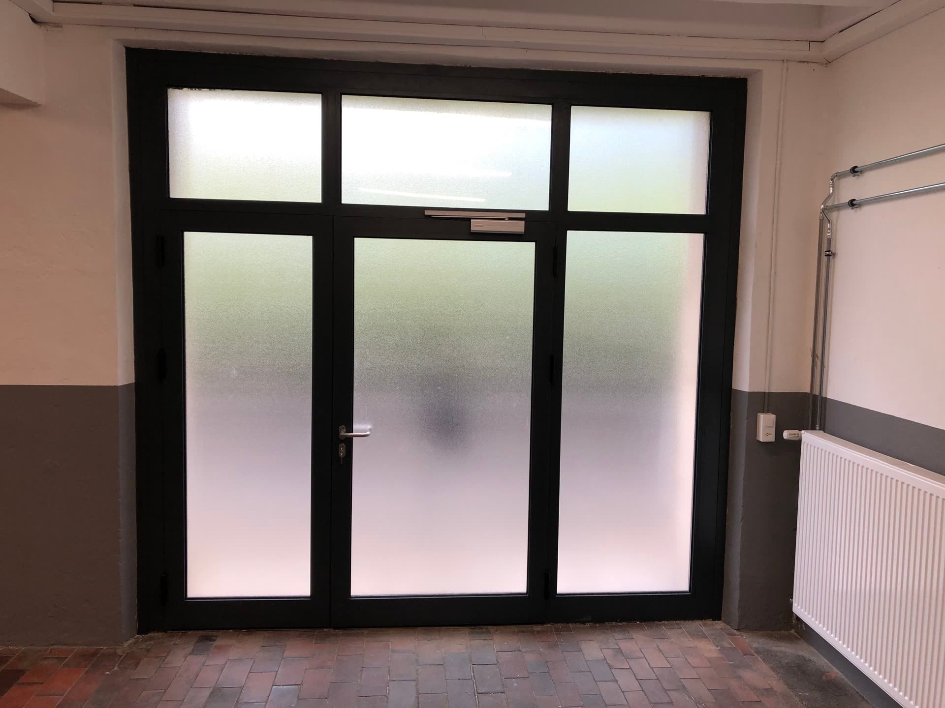 Porte double vitrée à cadre anthracite avec imposte — Rue des Roches, Saint-Imier (BE)