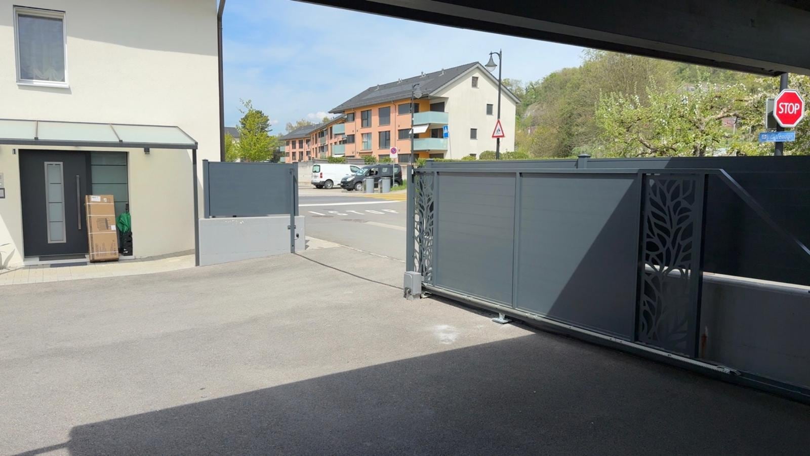 Portail et clôture pleine anthracite vus depuis un couvert — Eclepens (VD)